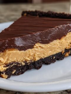Ein Stück Decadent Chocolate Peanut Butter Temptation Pie mit Schokoladenkruste und Erdnussbutterfüllung.