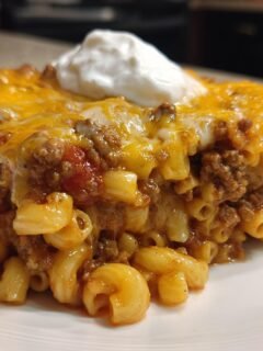 Ein gro&szlig;es St&uuml;ck Taco Pasta mit Hackfleisch, Makkaroni, geschmolzenem K&auml;se und einem Klecks Sauerrahm.