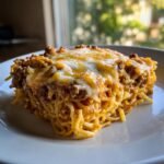 Ein gro&szlig;es, saftiges St&uuml;ck Taco Spaghetti mit Hackfleisch und geschmolzenem K&auml;se auf einem wei&szlig;en Teller.