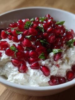 Nahaufnahme des Tangy Pomegranate Feta Cheese Dip mit wei&szlig;en K&auml;se und roten Granatapfelkernen.