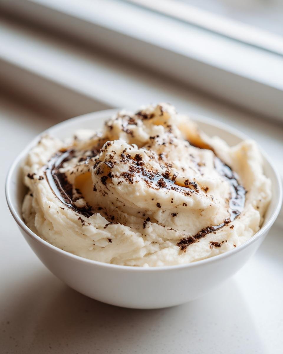 Nahaufnahme von cremigem Tr&uuml;ffel Kartoffelp&uuml;ree mit dunklem Tr&uuml;ffel&ouml;l und geriebenem Tr&uuml;ffel.