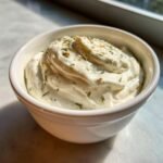 Nahaufnahme einer cremigen, wei&szlig;en Sauce, dem Wingstop Ranch Rezept, bestreut mit Kr&auml;utern in einer kleinen Schale.