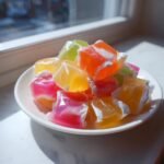 Bunte, quadratische St&uuml;cke Homemade Saltwater Taffy mit wei&szlig;en Streifen auf einem wei&szlig;en Teller.