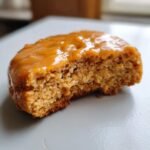 Nahaufnahme eines Delightful Gingerbread Cheesecake Cookies mit Karamellglasur und einem Bissen entfernt.