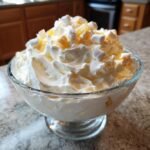 Nahaufnahme von Easy Creamy Cool Whip Pineapple Fluff mit Marshmallows in einer Glasschale.
