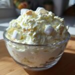 Nahaufnahme von Easy Creamy Cool Whip Pineapple Fluff mit Marshmallows in einer Glasschale.