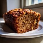 Ein saftiges St&uuml;ck Easy Healthy Protein Banana Bread auf einem wei&szlig;en Teller, im Gegenlicht gebacken.