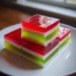Mehrere quadratische St&uuml;cke Easy Layered Christmas Jello mit roten, gr&uuml;nen und wei&szlig;en Schichten.