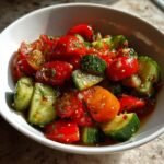 Nahaufnahme eines wei&szlig;en Sch&auml;lchens mit erfrischendem Gurken Tomaten Salat Rezept, mariniert und gl&auml;nzend.