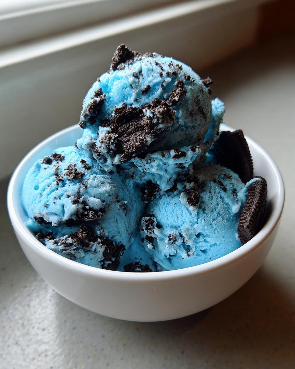 Drei Kugeln leuchtend blaues Fun Cookie Monster Ice Cream mit dunklen Keksst&uuml;cken in einer wei&szlig;en Schale.