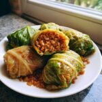 Nahaufnahme von Delicious Lentil Rice Stuffed Cabbage Rolls (Kohlrouladen) auf einem wei&szlig;en Teller.