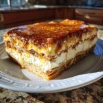 Ein St&uuml;ck Delicious Honey Cinnamon Sugar Sopapilla Cheesecake mit cremiger F&uuml;llung und Honig-Zimt-Glasur auf einem wei&szlig;en Teller.