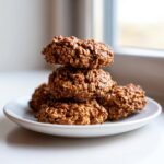 Stapel von schokoladigen, haferflockigen Delicious Peanut Butter No Bake Cookies auf einem wei&szlig;en Teller.