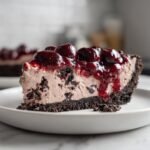 Nahaufnahme eines St&uuml;cks No Bake Chocolate Cherry Cream Pie mit dunklem Keksboden und Kirschtopping.