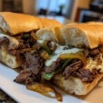 Aufgeschnittenes Quick Delicious Philly Cheesesteak Sandwich mit geschmolzenem K&auml;se, Steakstreifen und sautierten Zwiebeln/Paprika.