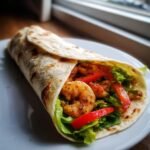Nahaufnahme eines Quick Easy Shrimp Wrap gef&uuml;llt mit Garnelen, Salat und Paprika.