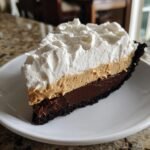 Ein gro&szlig;es St&uuml;ck Decadent No Bake Chocolate Peanut Butter Pie mit Schokoladenboden, Erdnussbutter- und Schokoladenschicht und viel Sahne.