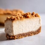 Nahaufnahme eines cremigen St&uuml;cks Decadent White Chocolate Peanut Butter Cheesecake mit Keksboden.