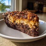 Nahaufnahme eines St&uuml;cks Irresistible No Bake German Chocolate Pie mit Schokoladenboden und Kokosnuss-Karamell-Topping.
