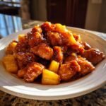 Nahaufnahme von paniertem H&auml;hnchen mit Ananasst&uuml;cken in einer gl&auml;nzenden, s&uuml;&szlig;-sauren Honig-Sauce: Sweet Savory Honey Pineapple Chicken.
