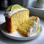Ein St&uuml;ck Zesty Key Lime Cake mit saftiger Krume und cremiger Frischk&auml;seglasur, garniert mit Limettenscheiben.