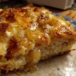 Nahaufnahme eines saftigen St&uuml;cks Cheesy French Onion Chicken Casserole Recipe mit goldbrauner K&auml;sekruste und karamellisierten Zwiebeln.