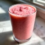 Nahaufnahme eines hohen Glases mit dem fertigen, rosa-farbenen Copycat Starbucks Pink Drink, leicht schaumig.