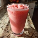 Ein hohes Glas mit einem eisgek&uuml;hlten, rosa Mixgetr&auml;nk, dem Copycat Starbucks Pink Drink, auf einer Granit-Arbeitsplatte.