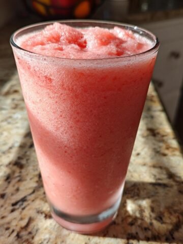 Ein hohes Glas mit einem eisgek&uuml;hlten, rosa Mixgetr&auml;nk, dem Copycat Starbucks Pink Drink, auf einer Granit-Arbeitsplatte.