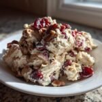 Nahaufnahme von Delicious Creamy Cranberry Pecan Chicken Salad (H&auml;hnchensalat) mit getrockneten Cranberrys und Pekann&uuml;ssen auf einem wei&szlig;en Teller.