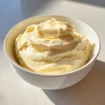 Nahaufnahme von dicker, cremiger Homemade Mayonnaise in einer wei&szlig;en Sch&uuml;ssel, perfekt emulgiert.