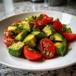 Nahaufnahme eines leuchtend gr&uuml;nen Cucumber Tomato Avocado Salad mit gew&uuml;rfeltem Avocado und halbierten Kirschtomaten.