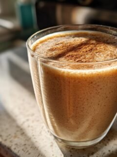 Ein Glas mit einem cremigen Delicious Apple Pie Smoothie, bestreut mit Zimt.