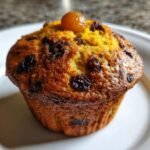 Nahaufnahme eines saftigen Delightful Simnel Muffins mit Rosinen und einer kandierten Frucht obenauf.