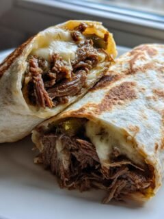 Zwei H&auml;lften von Easy Philly Cheesesteak Roll Ups, gef&uuml;llt mit geschmortem Rindfleisch und geschmolzenem K&auml;se.