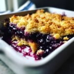 Nahaufnahme eines gebackenen Easy Southern Style Blueberry Cobbler mit goldbrauner Kruste und dunkler Blaubeerf&uuml;llung.