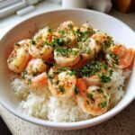 Nahaufnahme einer wei&szlig;en Sch&uuml;ssel mit wei&szlig;em Reis und saftigen Garnelen, garniert mit viel frischer Petersilie f&uuml;r den Garlic Shrimp Rice Bowl.