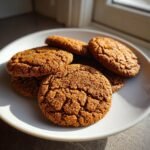 Nahaufnahme von mehreren knusprigen Gingerbrave Cookies mit Zuckerkruste auf einem wei&szlig;en Teller.