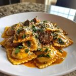 Nahaufnahme von herzhaftem cremigen Cajun Wurst Ravioli Rezept in einer wei&szlig;en Sch&uuml;ssel, garniert mit Petersilie und K&auml;se.