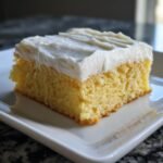 Ein St&uuml;ck gelber Kuchen mit dicker, wei&szlig;er Glasur, bekannt als Irresistible Cake Batter Bars, auf einem wei&szlig;en Teller.