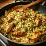 Nahaufnahme des fertigen Lemon Chicken Orzo Skillet mit gebratenen H&auml;hnchenst&uuml;cken und viel Petersilie.