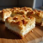 Anschnittst&uuml;ck der Lightest Ricotta Squares mit knusprigem Mandel-Streusel-Topping auf Holzbrett.