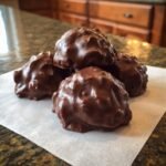 Nahaufnahme von vier schokoladen&uuml;berzogenen Martha Washington Pralinen auf Backpapier.