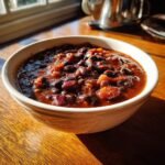 Nahaufnahme einer wei&szlig;en Sch&uuml;ssel mit herzhaftem Quick Easy Black Bean Chili auf einem Holztisch.