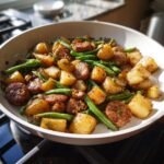 Gebratenes Quick And Tasty Sausage Potato Green Bean Skillet mit goldbraunen Kartoffelst&uuml;cken, Wurstscheiben und gr&uuml;nen Bohnen in einer Pfanne.