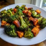 Nahaufnahme von ger&ouml;stetem Brokkoli und w&uuml;rfeligen S&uuml;&szlig;kartoffeln auf einem wei&szlig;en Teller, Teil des Savory Roasted Broccoli Sweet Potatoes Recipe.