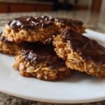 Ein Stapel von Quick Florentines Almond Cookies With Chocolate auf einem wei&szlig;en Teller, bedeckt mit dunkler Schokolade.