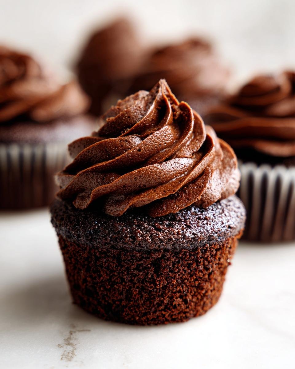 Nahaufnahme eines saftigen Schokoladen-Cupcakes mit &uuml;ppigem, dunklem Schokoladen-Frosting, der zu den Irresistible Hostess Chocolate Cupcakes geh&ouml;rt.