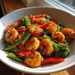 Nahaufnahme eines Sch&uuml;ssel mit leckerem Shrimp Stir Fry, garniert mit Sesam und Fr&uuml;hlingszwiebeln.