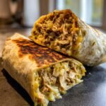 Nahaufnahme eines aufgeschnittenen Smoked Chicken Green Chile Burritos mit viel saftigem Fleisch und geschmolzenem K&auml;se.